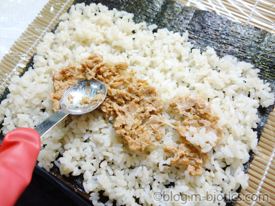 普通の納豆をフォークの背でつぶしてひきわり納豆にしたものを海苔＋寿司飯にのせているところ